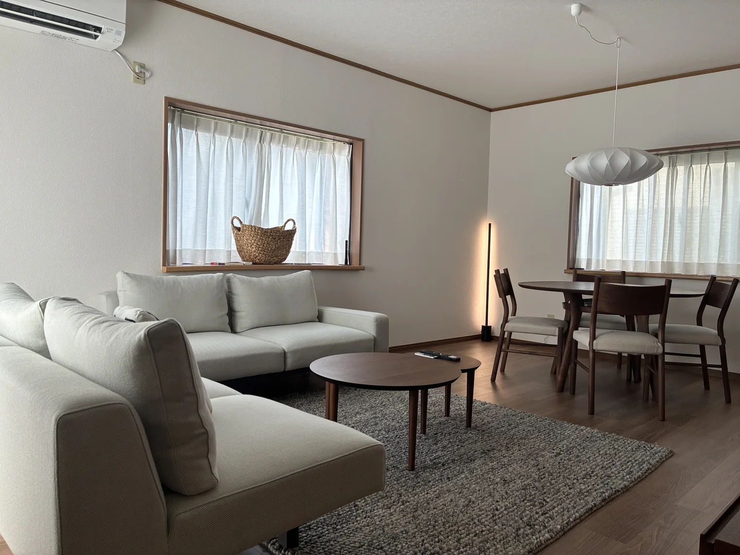 Real photo of the installed living and dining room with white sofas and dark wood furniture