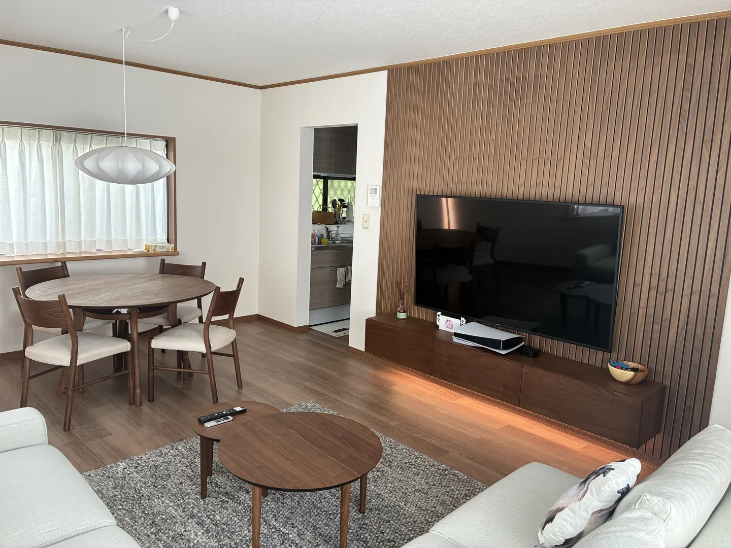 Real photo of the installed living and dining room with the planned furniture and wood TV wall