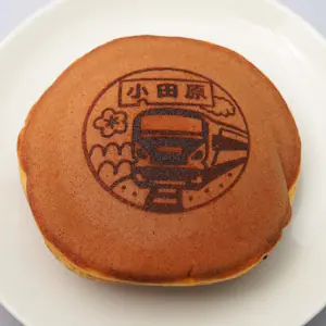Dorayaki, a traditional sweet made of two pancake-like castella patties wrapped around azuki bean paste, printed with a train and flower design reading "Odawara."
