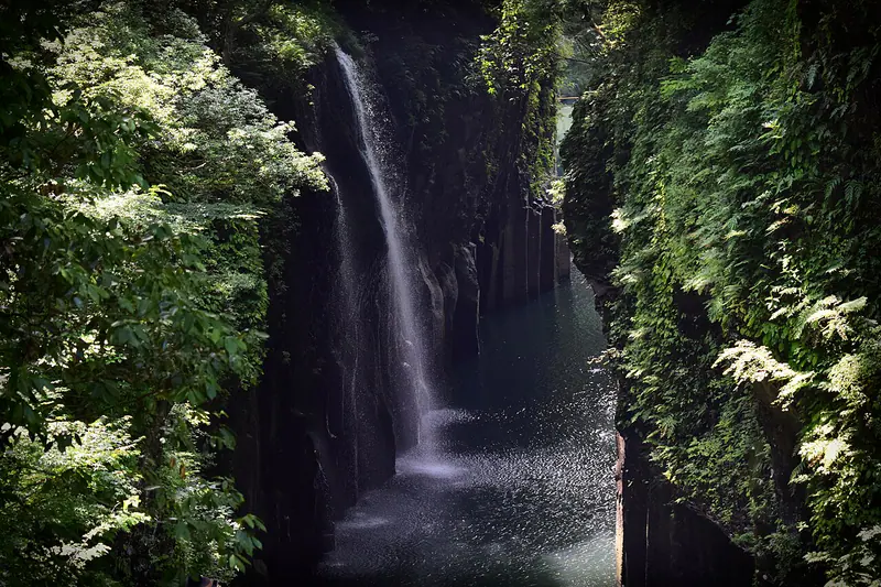 Boats below the steep cliffs and waterfall of Takachiho Gorge in Miyazaki Prefecture