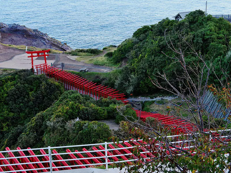 A long row of red torii gates descending the coastal cliffs at Motonosumi Inari Shrine in Yamaguchi