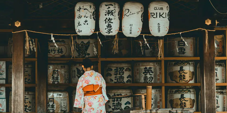 A person in a kimono standing at a traditional Japanese shrine building